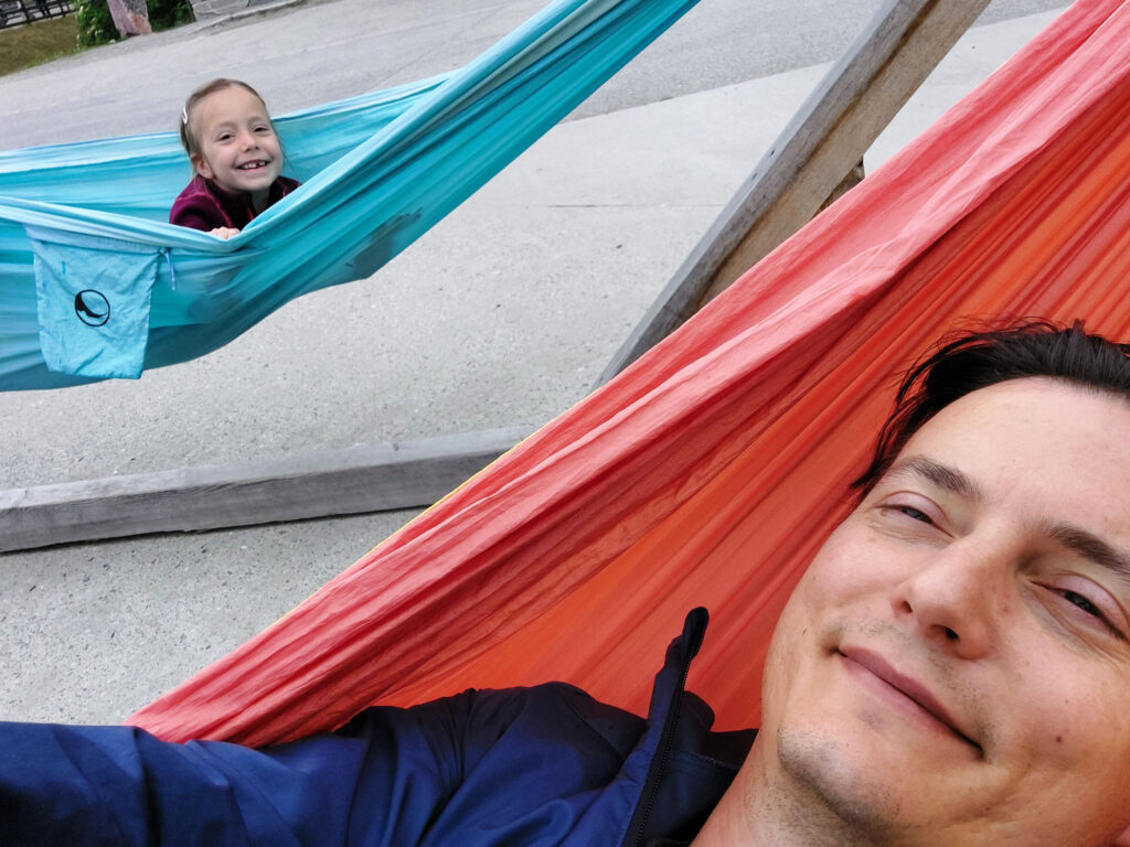 A child and parent are happy resting, each in their own hammock.