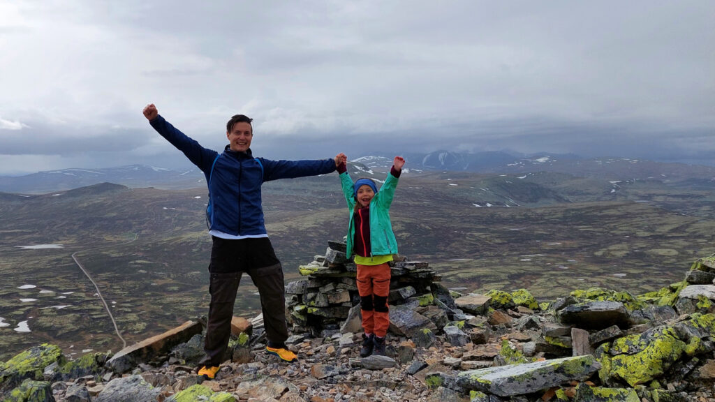 Father and daughter are happy on a summit after a hike in Norway.